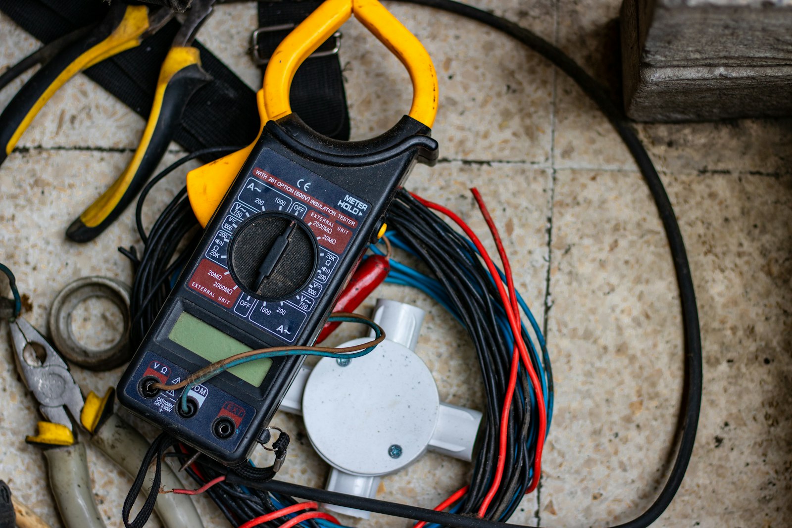 Yellow and black clamp meter with test leads on a workbench