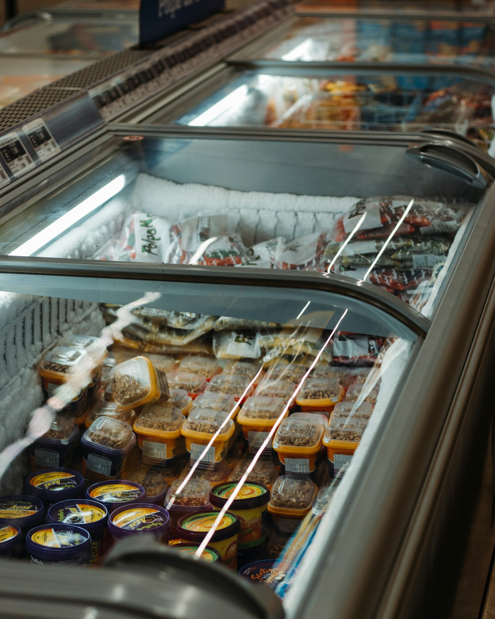 Commercial glass-top display freezer stocked with packaged food