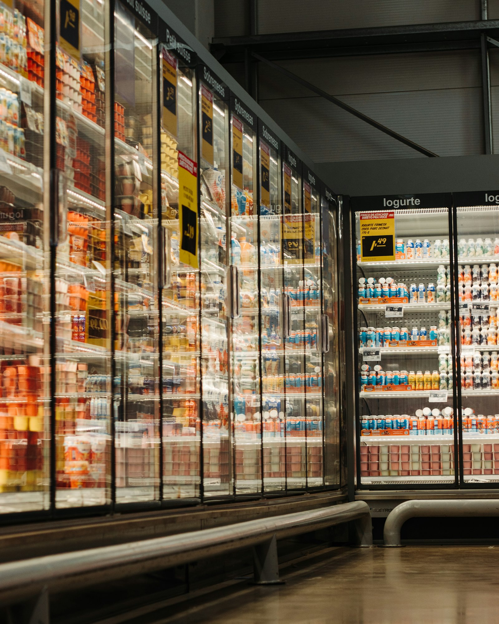 Row of glass-door refrigerated display cases stocked with yogurt in a grocery store