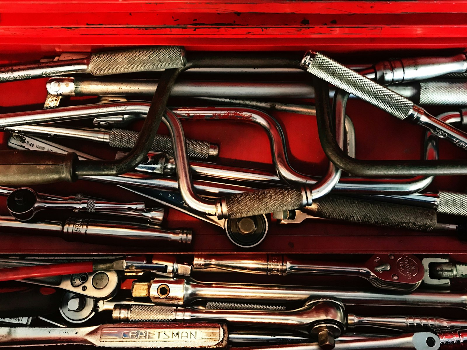 Assortment of hand tools including pliers and spanners in a red toolbox