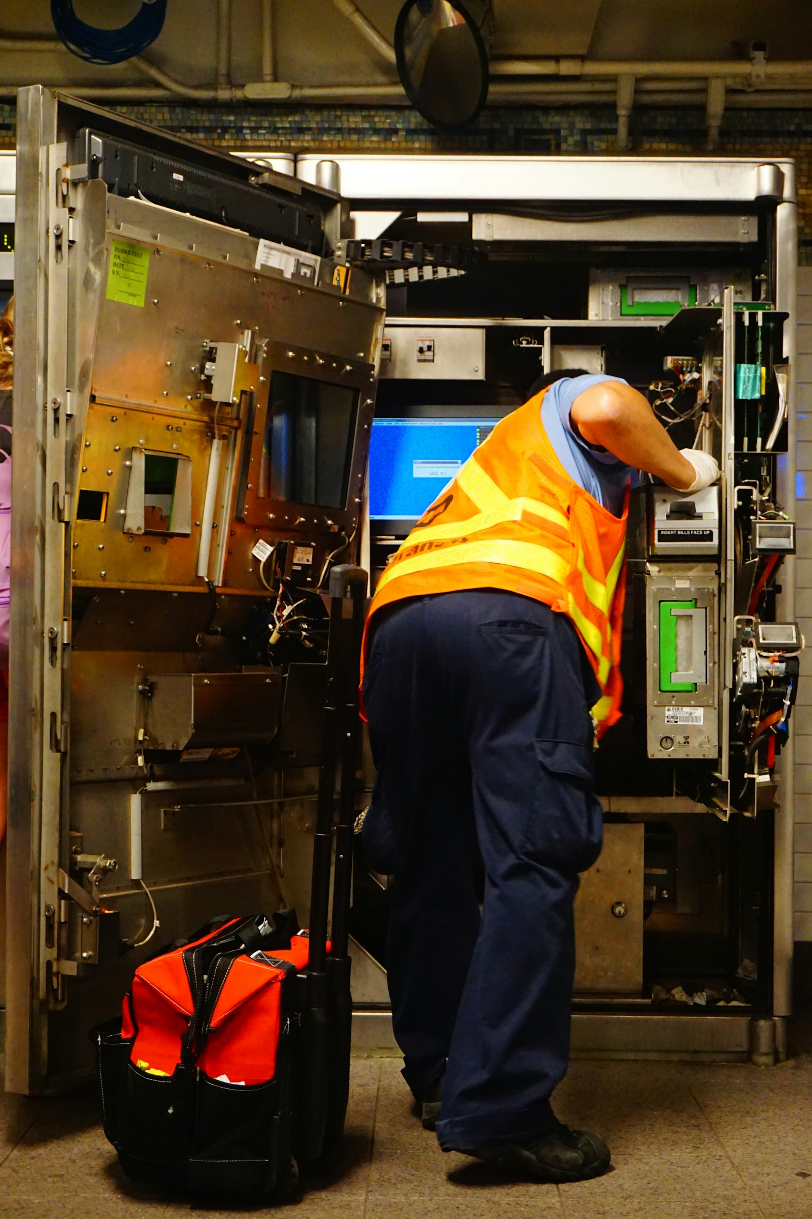 Technician in a high-visibility vest working inside a refrigerated machine