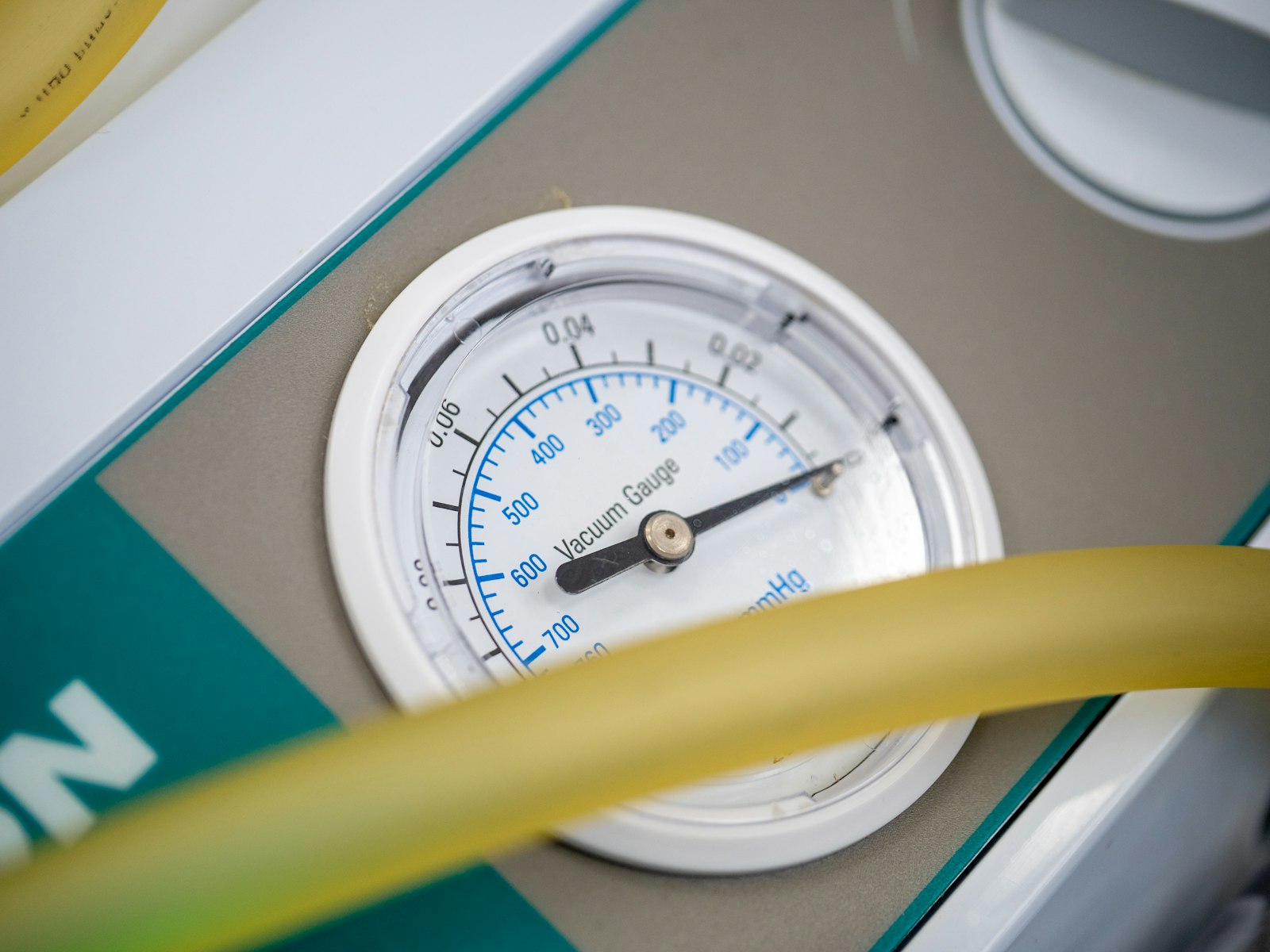 Round temperature gauge beside a yellow refrigerant hose